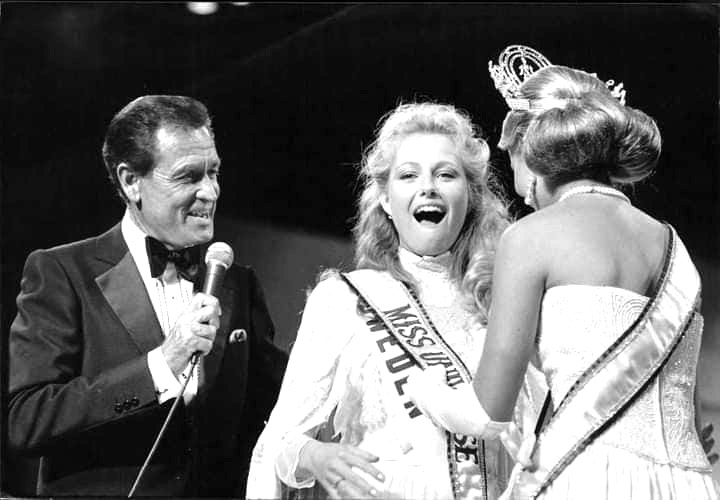 Bob Barker with Miss Universe 1984-Sweden's Yvonne Ryding as she is sashed by Miss Universe 1983-New Zealand's Lorraine Downes